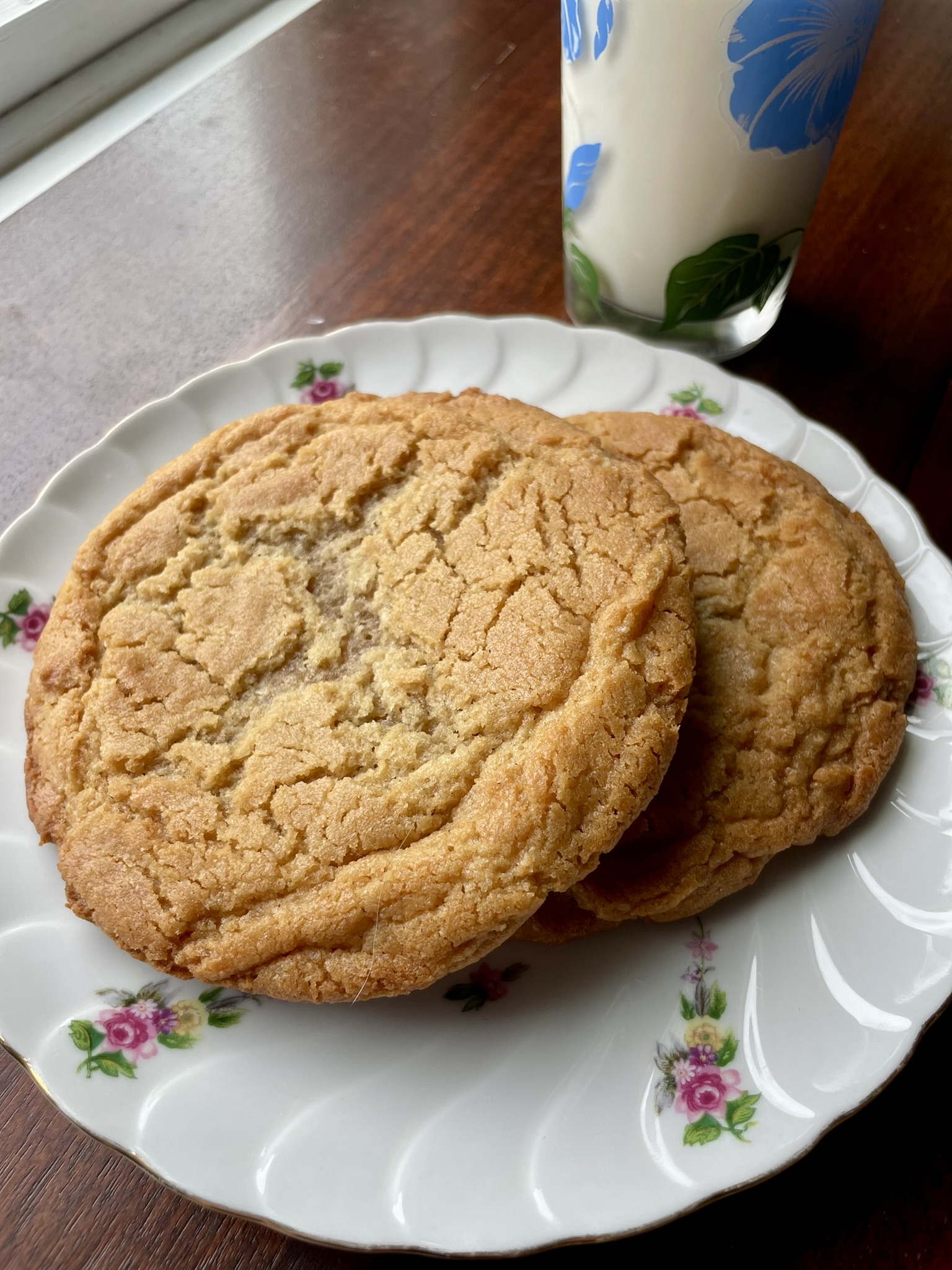 Wild Nunn Bakery peanut butter cookies on a floral china plate with a glass of milk
